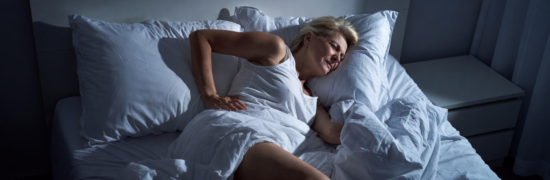 Woman lying in bed with back hurting